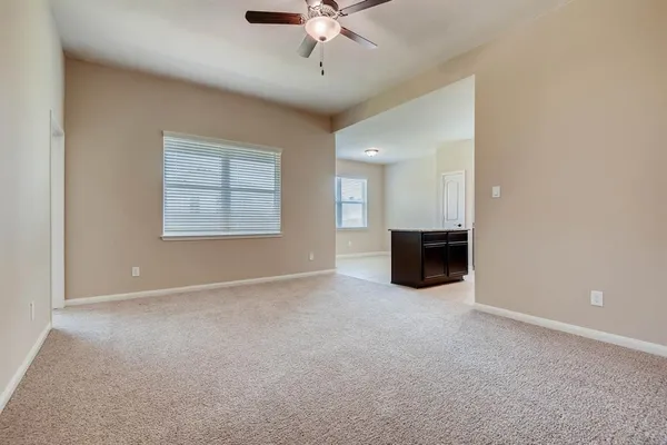 an empty room with a ceiling fan and windows