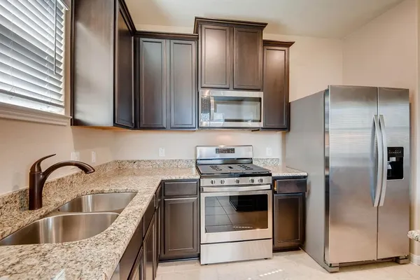 a kitchen with granite countertop a stove sink and refrigerator