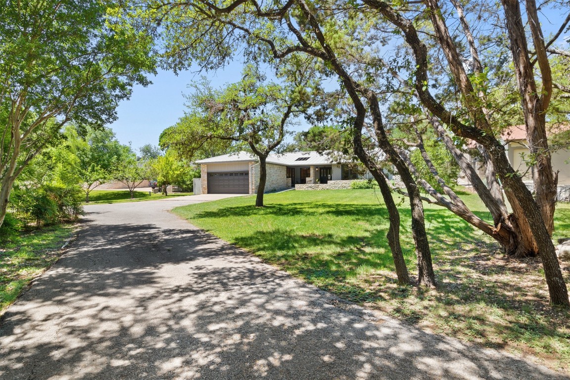 1009 Corsaire Cove Lakeway, TX 78734 - Photo 1 of 1 a view of a yard with plants and a large tree