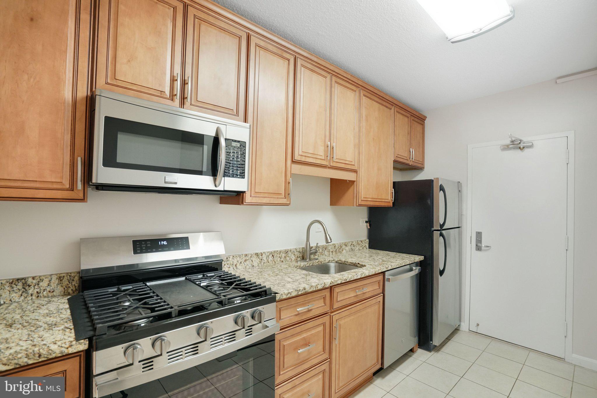 4141 North Henderson Road, Unit 303 Arlington, VA 22203 - Photo 8 of 37 a kitchen with stainless steel appliances granite countertop a stove microwave refrigerator and sink