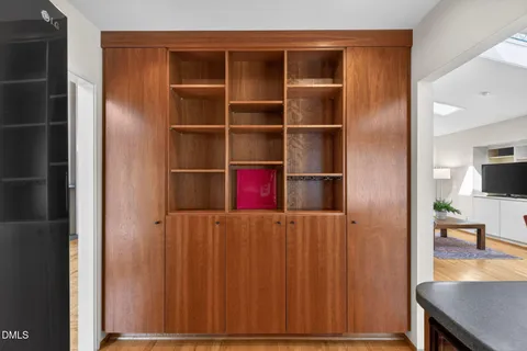 a kitchen with stainless steel appliances a refrigerator a stove and a dining table with wooden floor