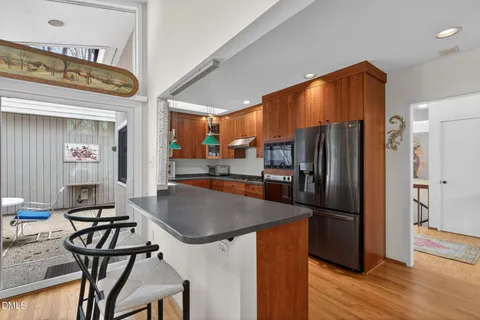 a kitchen with stainless steel appliances granite countertop a sink dishwasher a stove and a dining table with wooden floor