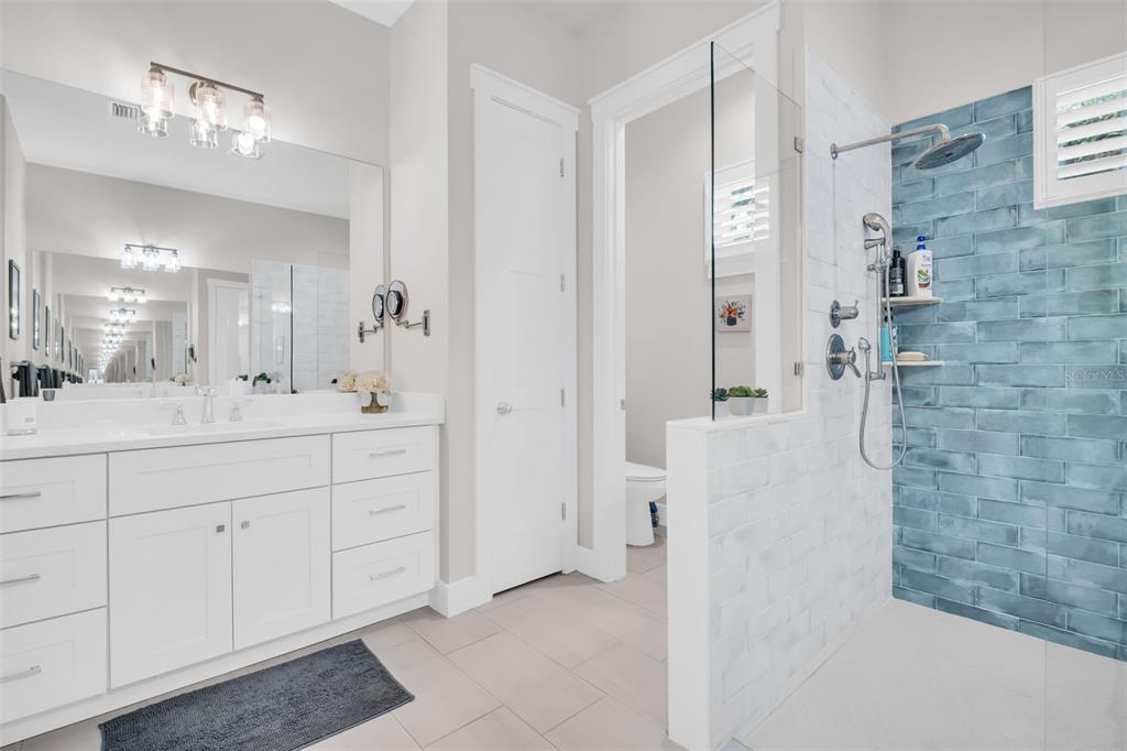 9840 West Bay Street Seminole, FL 33776 - Photo 46 of 75 a bathroom with a double vanity sink a mirror a shower and a bathtub