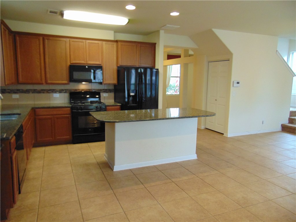 5208 Hellman Kyle, TX 78640 - Photo 11 of 26 a large kitchen with stainless steel appliances a stove a sink a microwave and cabinets