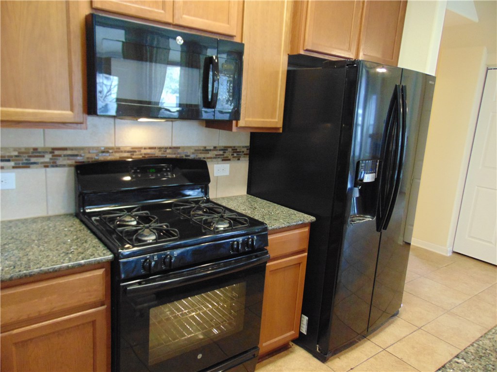 5208 Hellman Kyle, TX 78640 - Photo 13 of 26 a kitchen with stainless steel appliances granite countertop a stove a refrigerator and a sink