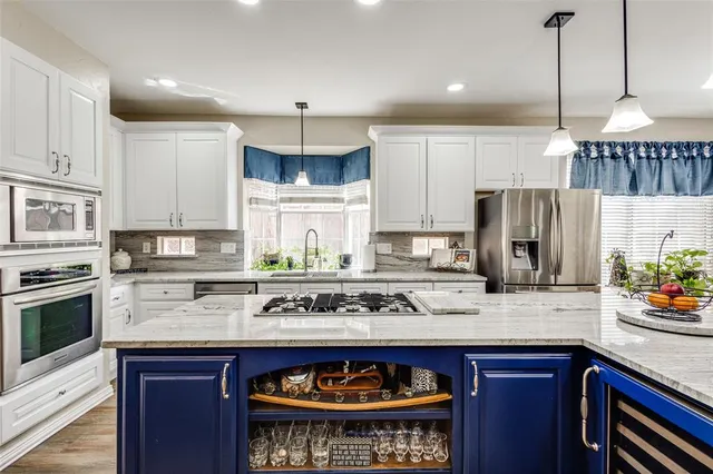 a kitchen with stainless steel appliances granite countertop a stove a sink a refrigerator and center island