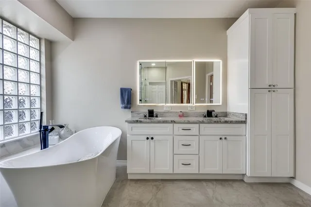 a spacious bathroom with a double vanity sink a mirror and a bathtub