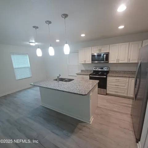 a kitchen with a sink and wooden floor