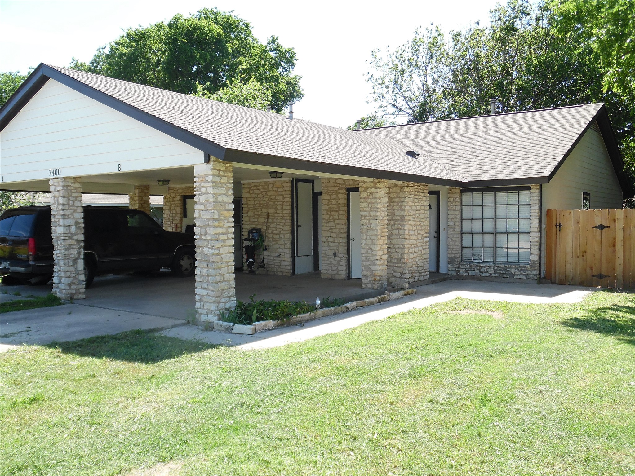 7400 Dixie Drive, Unit B Austin, TX 78744 - Photo 1 of 15 Exterior facade featuring stone veneer columns and accents, a covered carport, and a composite shingle roof