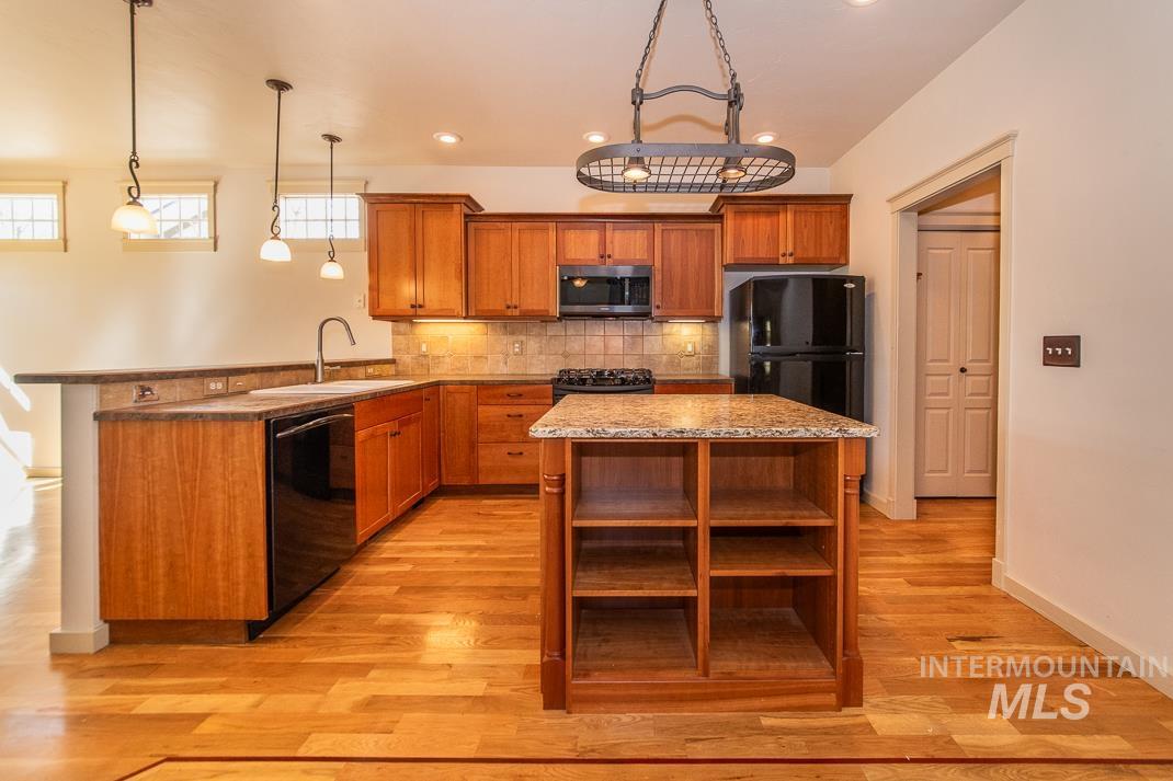 727 West Sedgewick Street Meridian, ID 83646 - Photo 5 of 30 Kitchen with wood finish cabinetry, a peninsula, black appliances, and light wood-type flooring