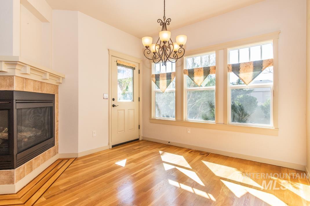 727 West Sedgewick Street Meridian, ID 83646 - Photo 7 of 30 Unfurnished dining area featuring a tiled fireplace, light wood-style floors, and suspended lighting