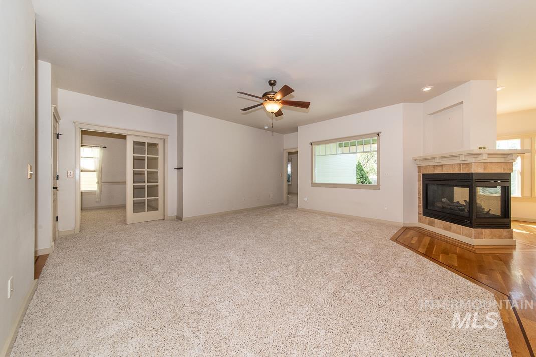 727 West Sedgewick Street Meridian, ID 83646 - Photo 10 of 30 Unfurnished living room featuring light colored carpet, a tiled fireplace, and ceiling fan