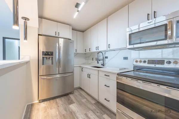 a kitchen with cabinets stainless steel appliances and wooden floor
