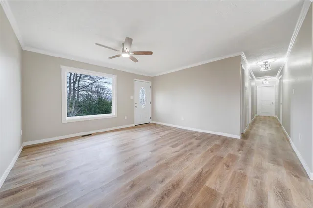 a view of an empty room with a window and wooden floor