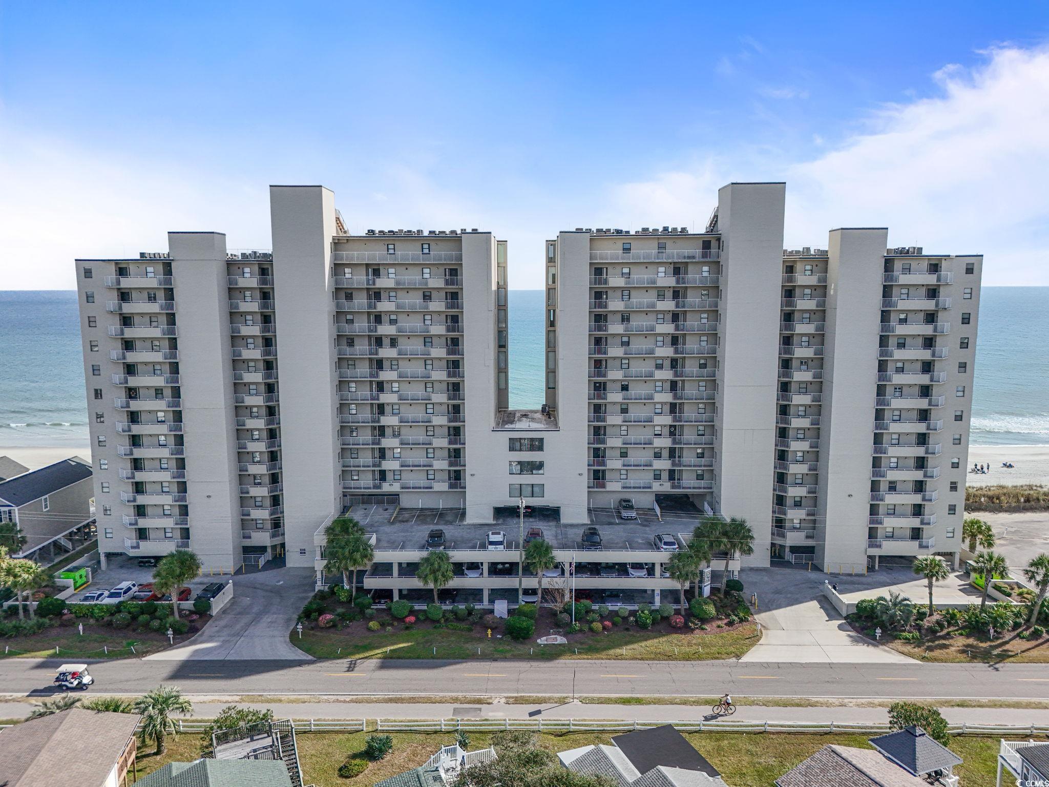 View of apartment building / complex with view of water and beach