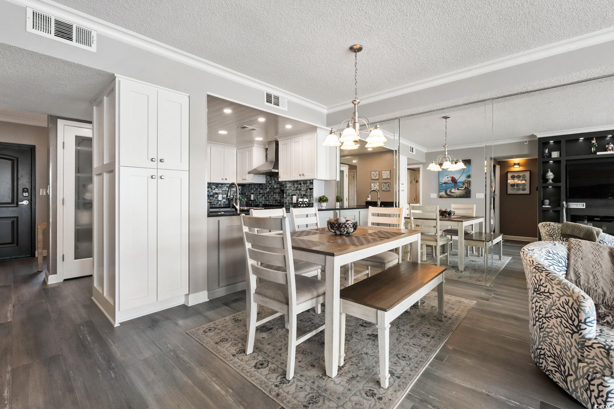1990 North Waccamaw Drive, Unit 403 Murrells Inlet, SC 29576 - Photo 13 of 39 Dining space featuring crown molding, a textured ceiling, dark wood-style floors, and a chandelier