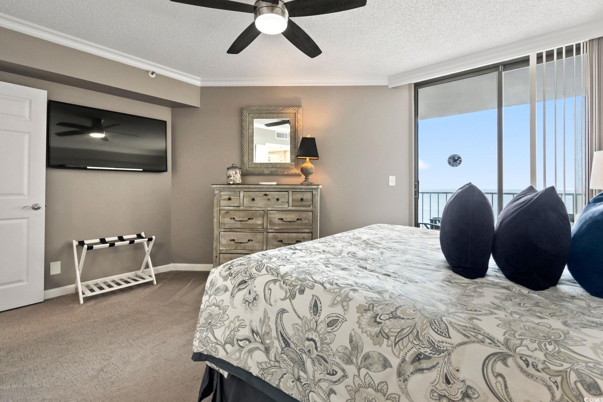 1990 North Waccamaw Drive, Unit 403 Murrells Inlet, SC 29576 - Photo 15 of 39 Bedroom featuring access to outside, a textured ceiling, ornamental molding, light colored carpet, and multiple windows