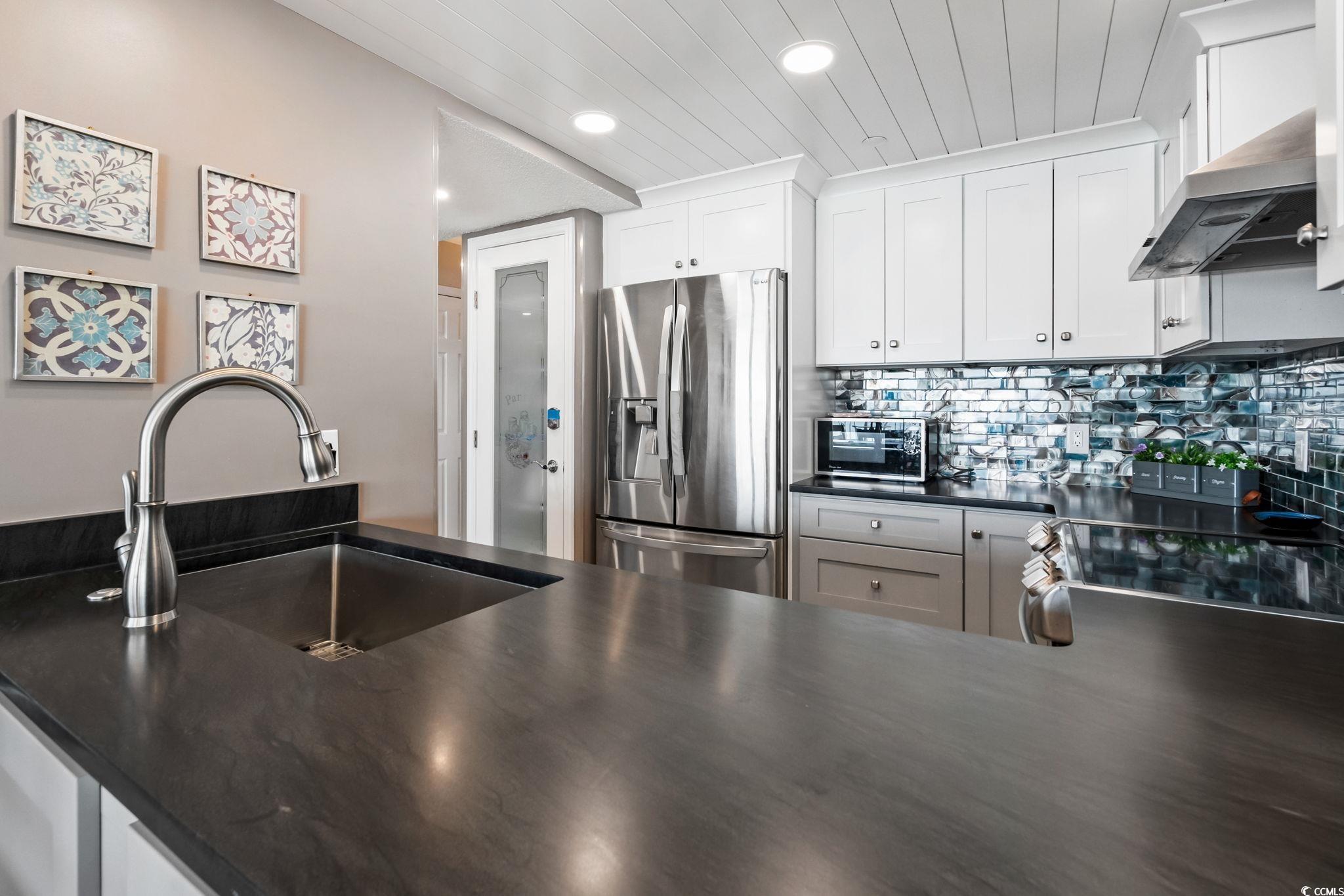 1990 North Waccamaw Drive, Unit 403 Murrells Inlet, SC 29576 - Photo 23 of 39 Kitchen featuring stainless steel appliances, ventilation hood, tasteful backsplash, white cabinetry, and wooden ceiling