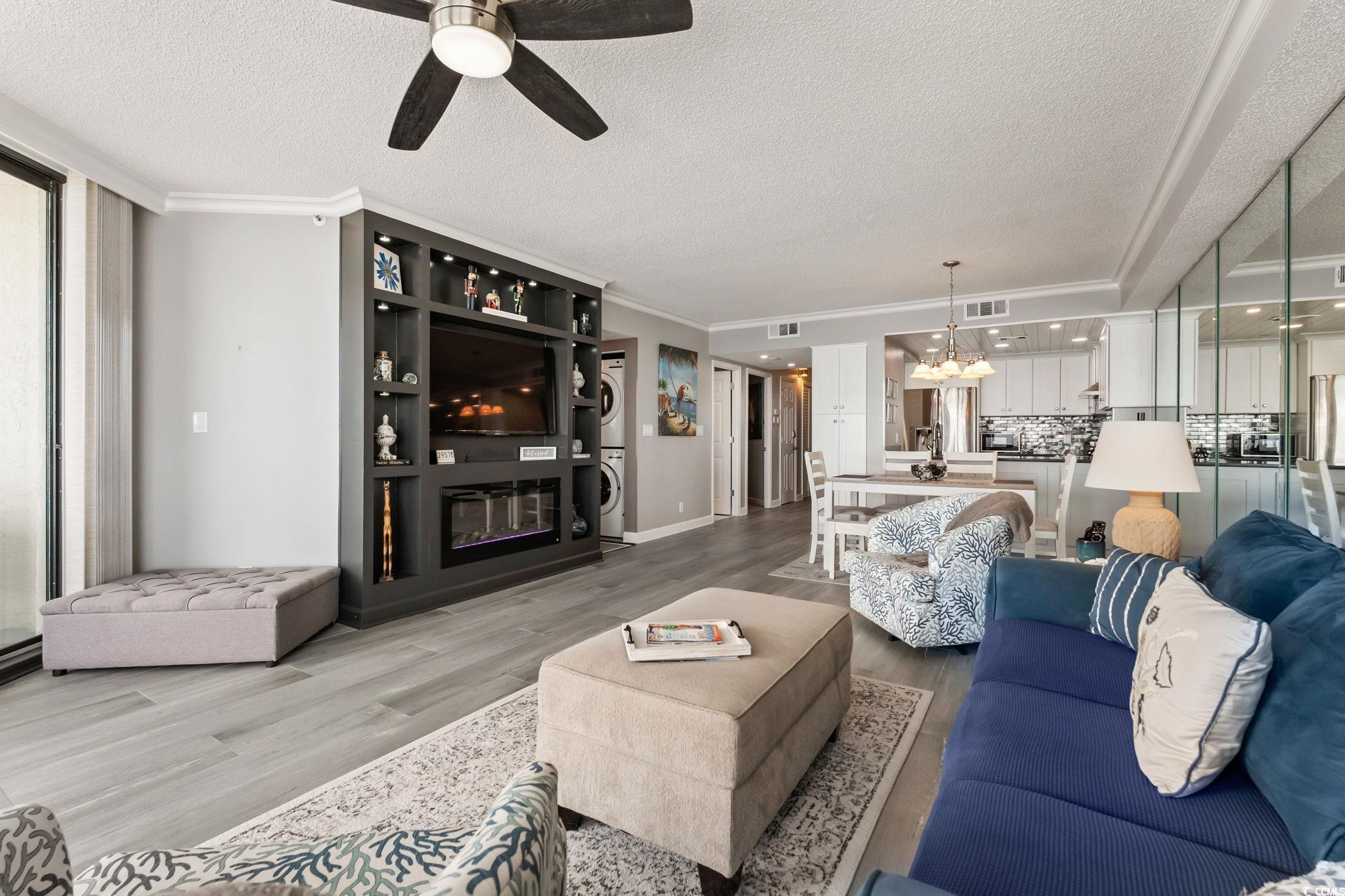1990 North Waccamaw Drive, Unit 403 Murrells Inlet, SC 29576 - Photo 9 of 39 Living room with wood finished floors, a textured ceiling, a glass covered fireplace, ceiling fan, and stacked washer / drying machine