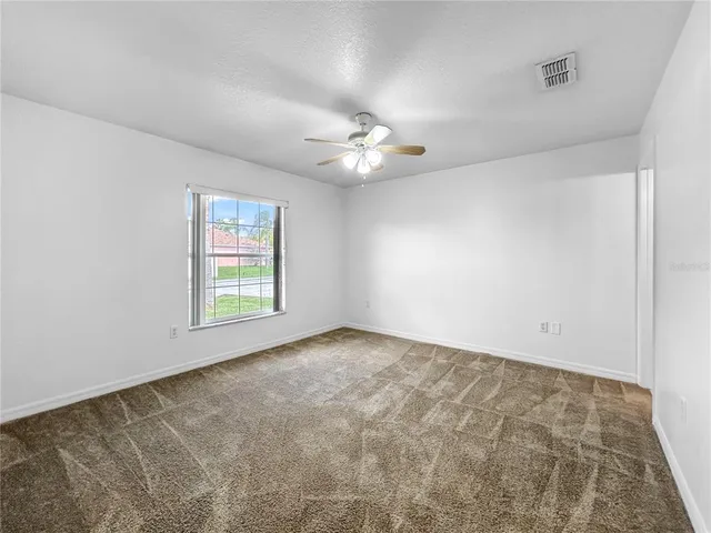 an empty room with windows and ceiling fan