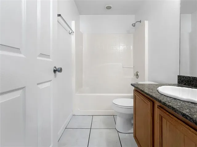 a bathroom with a granite countertop sink a toilet a mirror and shower