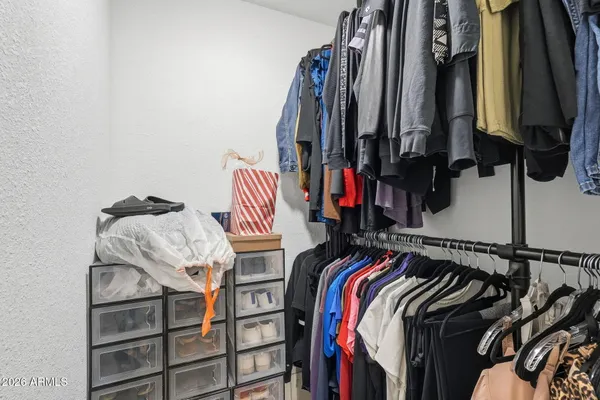 a view of walk in closet with clothes and shoes