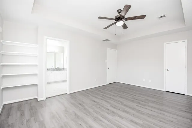 an empty room with wooden floor ceiling fan and windows