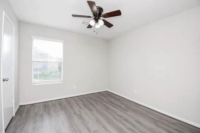 an empty room with a window and a fan