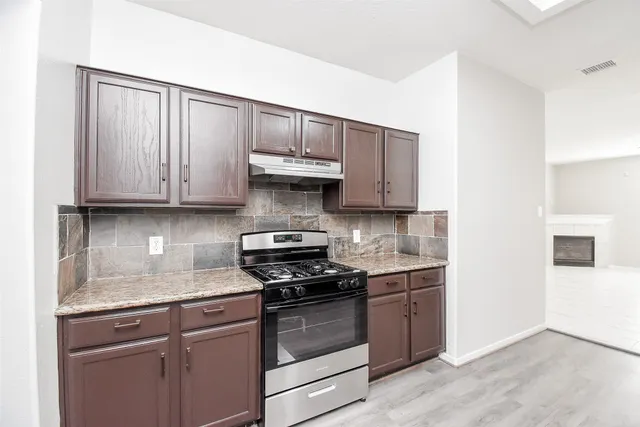 a kitchen with granite countertop wooden cabinets and a stove top oven