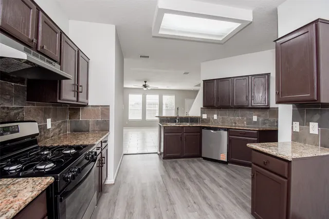 a kitchen with granite countertop wooden cabinets stove top oven and sink