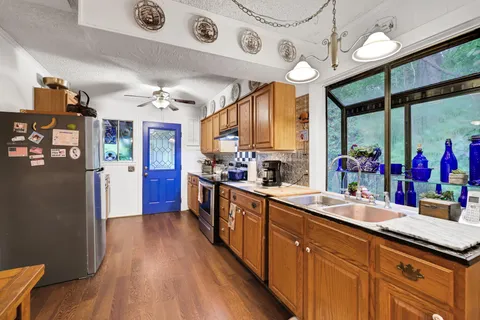 a kitchen with stainless steel appliances granite countertop a sink and wooden floors