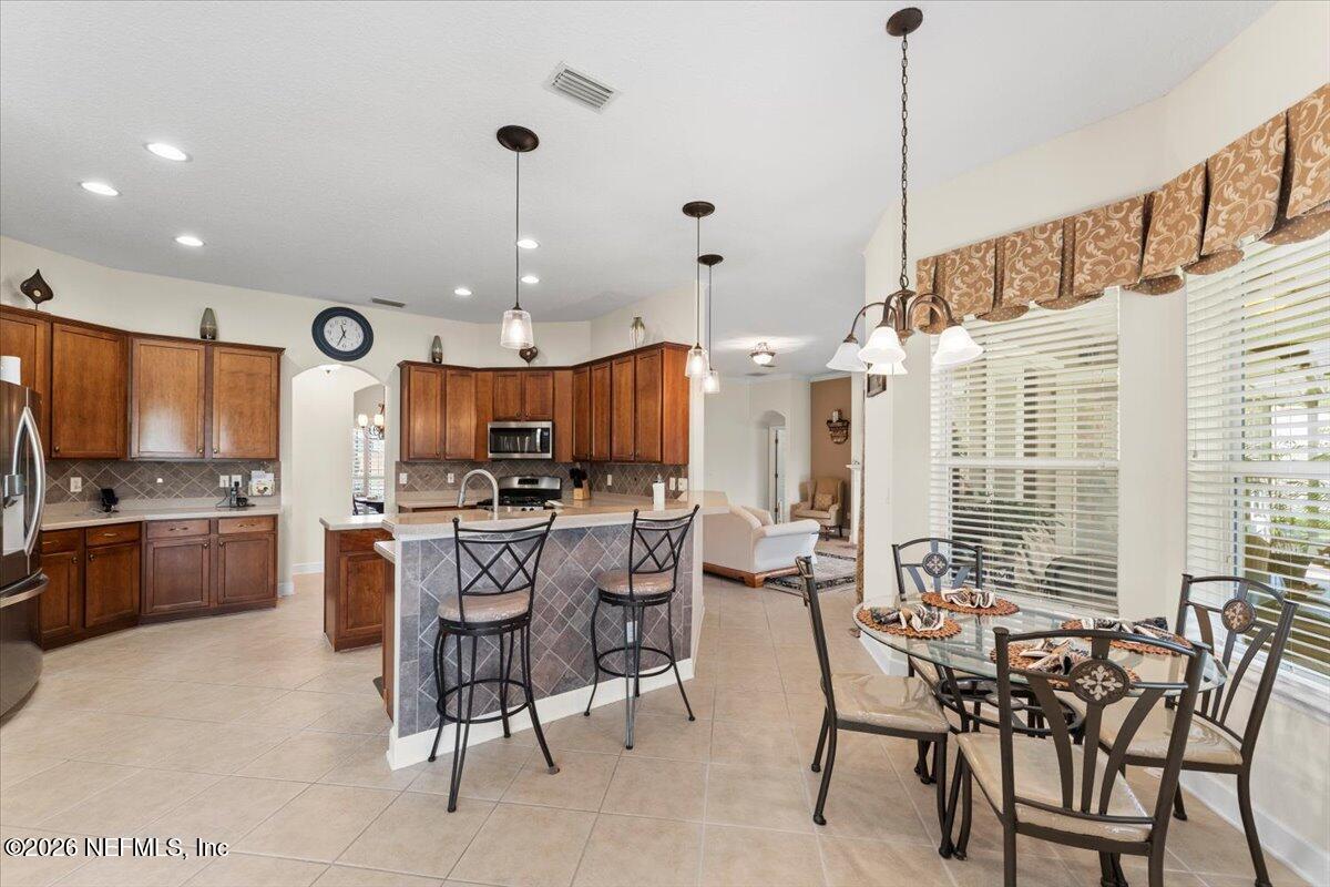 1112 Hawk Watch Circle St. Augustine, FL 32092 - Photo 24 of 49 a kitchen with stainless steel appliances kitchen island granite countertop a table chairs and a refrigerator