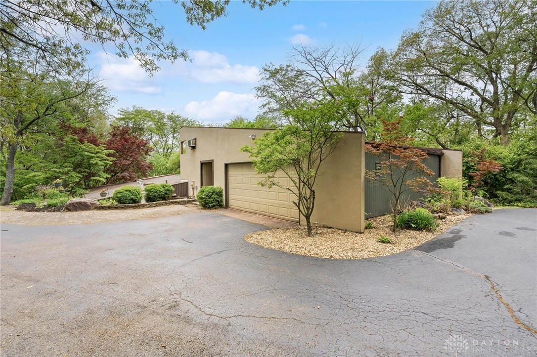 This modern home features a spacious garage and a lush, green landscape.