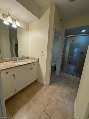 a spacious bathroom with a granite countertop sink a mirror and a shower