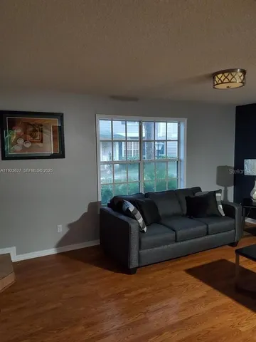 an empty room with a chandelier fan and windows