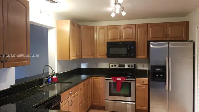 a kitchen with granite countertop a refrigerator stove and sink