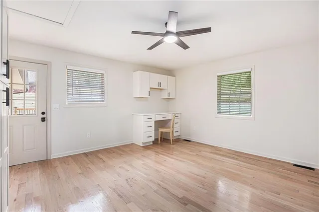 a view of an empty room with a window and wooden floor