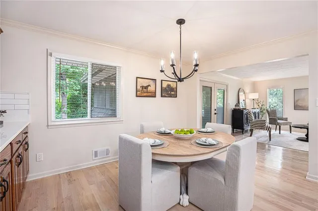 a view of a dining room and livingroom with furniture wooden floor a chandelier