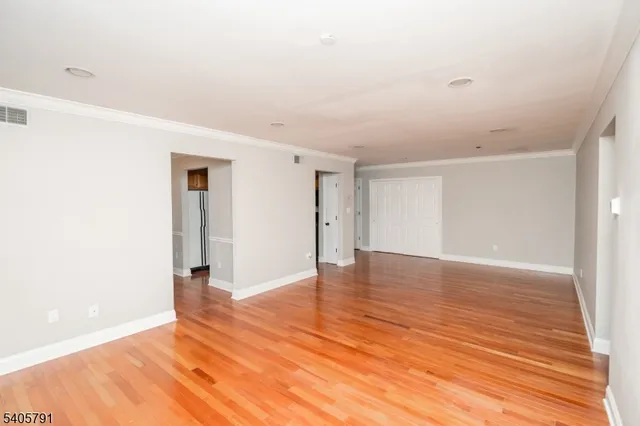 a view of an empty room with wooden floor and closet