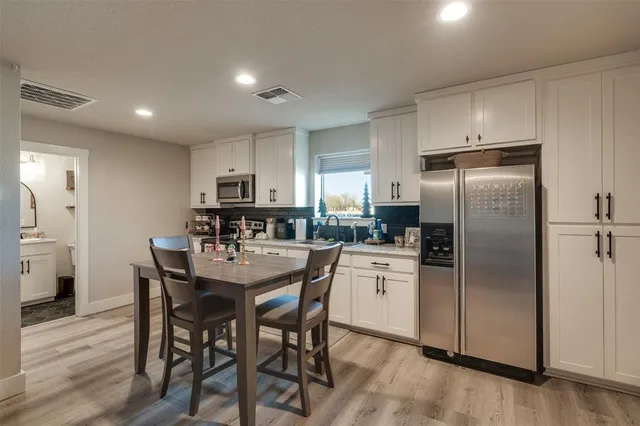 a kitchen with refrigerator a sink and chairs
