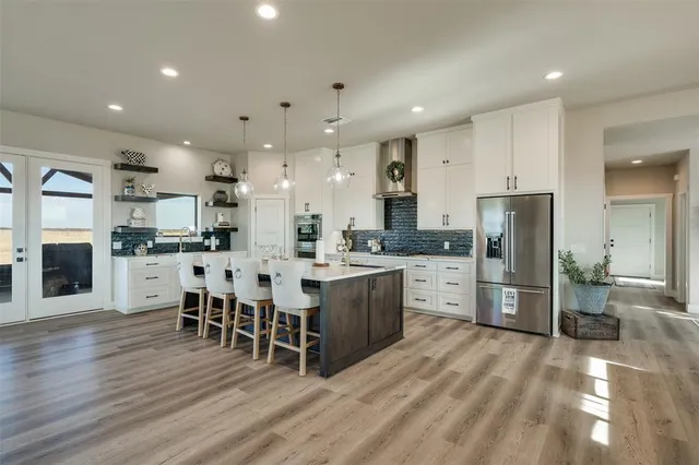 a large kitchen with cabinets chairs and wooden floor