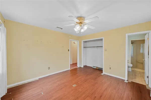 an empty room with wooden floor and a ceiling fan