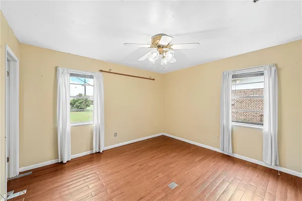 a view of empty room with wooden floor and fan