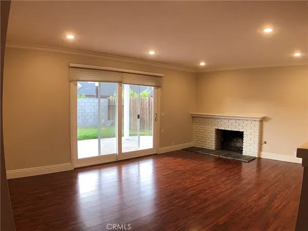 an empty room with wooden floor fireplace and windows