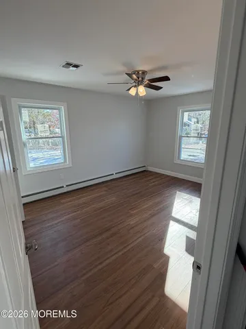 a view of empty room with wooden floor and fan