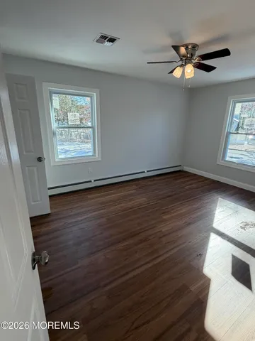 a view of an empty room with wooden floor and a window