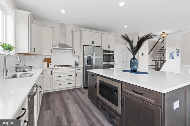 a kitchen with stainless steel appliances a white stove top oven a sink dishwasher and white cabinets with wooden floor