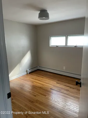 a view of empty room with wooden floor