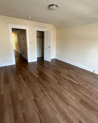 a view of an empty room with wooden floor and closet