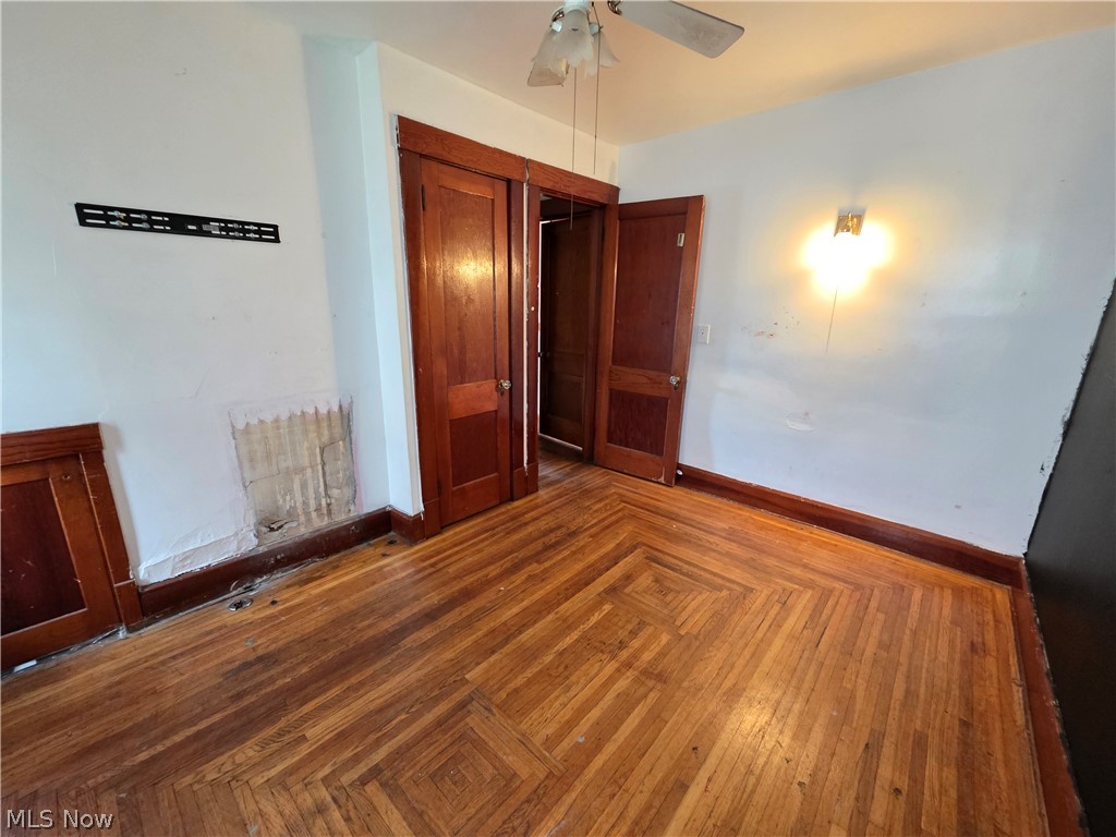 1801 West Prospect Road Ashtabula, OH 44004 - Photo 15 of 35 Wood-finish flooring with a geometric pattern, wood-paneled doors, wood trim, and a ceiling fan